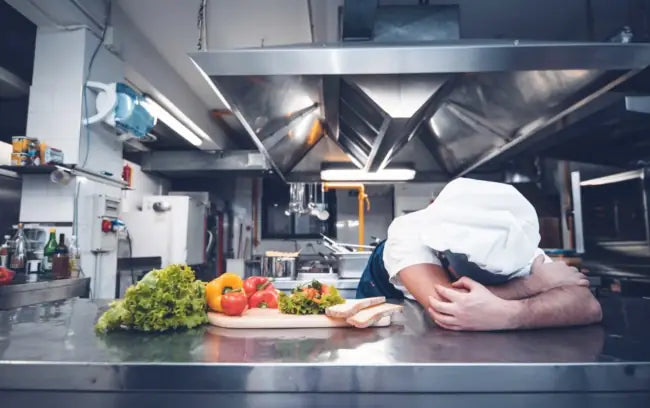 hef leaning over stainless steel bench in commercial kitchen during equipment breakdown, highlighting need for emergency repair service in North East Victoria
