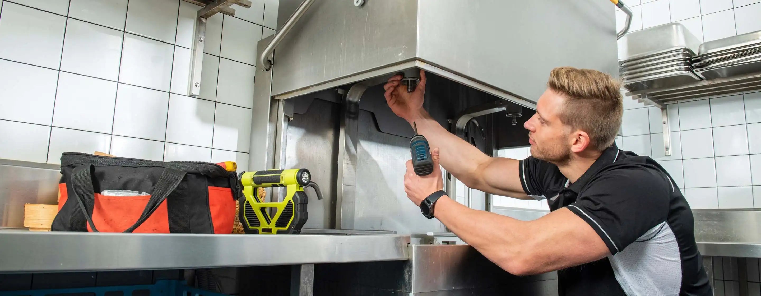 Technician repairing commercial kitchen equipment in stainless steel hospitality kitchen in North East Victoria by Northeast Catering Equipment